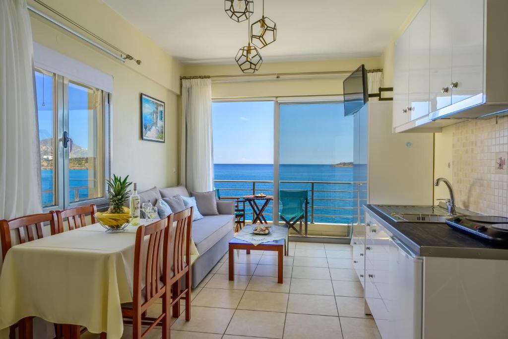 eine Küche und ein Wohnzimmer mit einem Tisch und einem Sofa in der Unterkunft Perla Apartments in Agios Nikolaos