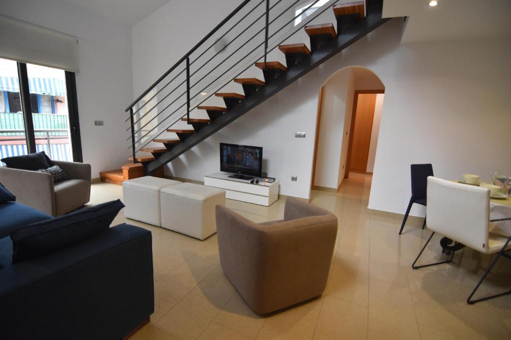 uma sala de estar com um sofá e uma televisão e escadas em RNET Apartments Roses Duplex Granada em Roses