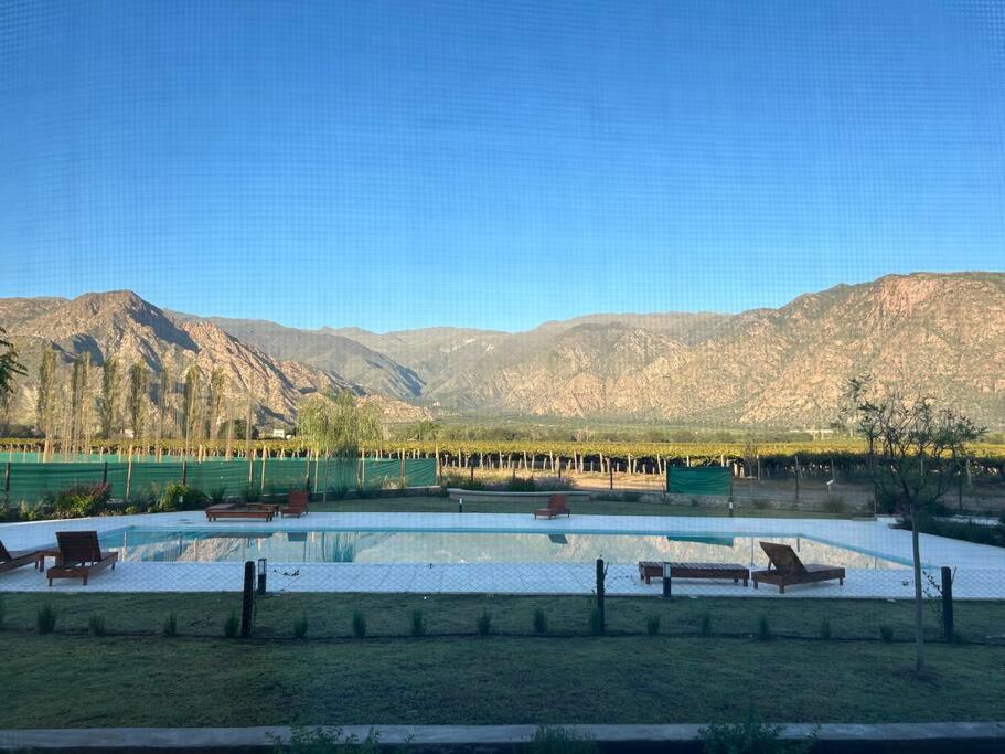 a pool of water with benches and mountains in the background at El loft mas lindo de Cafayate! in Cafayate