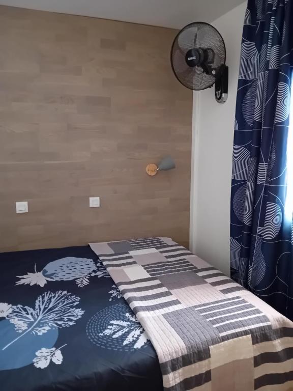 a bedroom with a bed with a blue and white blanket at Appartement T2 avec piscine a 100 m de la plage in Six-Fours-les-Plages