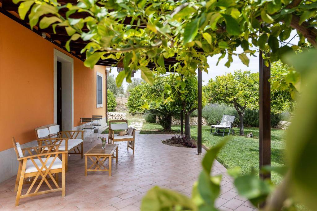 an outdoor patio with tables and chairs and trees at Fiore di Vendicari B&B - Sicilian Charme, Lemon Grove and Sea in Noto