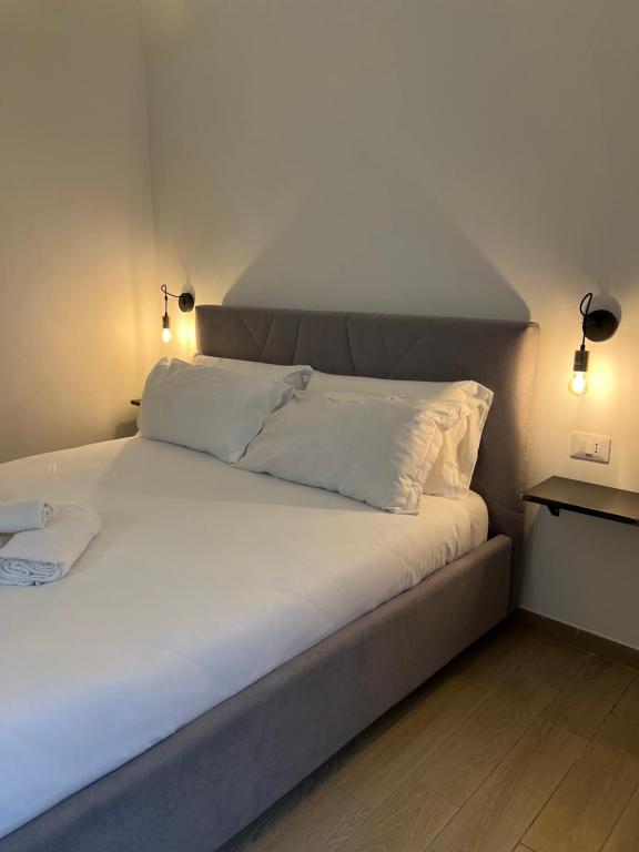 un letto con lenzuola e cuscini bianchi in una stanza di Villafranca settantuno Apartments a Palermo