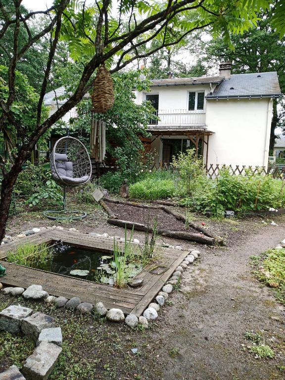 un jardin avec un étang, une chaise et une maison dans l'établissement Maison près des bois, à Joué-lès-Tours