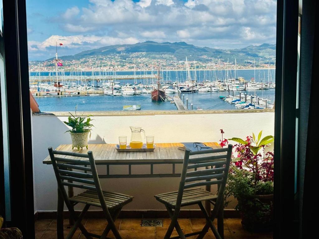 - une table avec deux chaises et une vue sur le port de plaisance dans l'établissement Holibai, Lembrare, El Mirador Del Mar, Ático, à Baiona