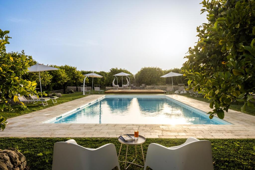 una piscina con sedie e un tavolo accanto ad essa di Fiore di Vendicari - Near the beaches of Calamosche and Vendicari a Noto
