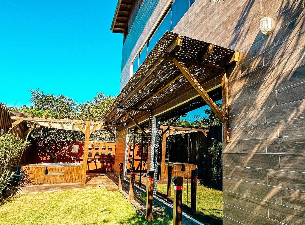a wooden pergola on the side of a building at Sheeps Family - Loft, Casa e Apartamento para Temporada - Praia do Rosa in Praia do Rosa