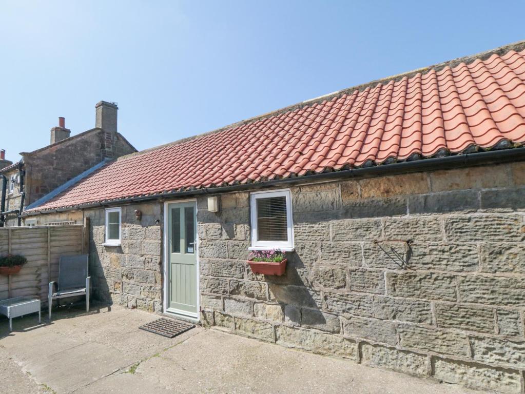 a stone house with a red roof at Abbey View Cottage in Hawsker