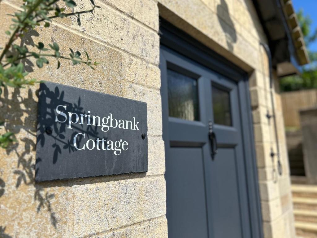 una señal en el lateral de un edificio con una puerta en Springbank Cottage, en Stroud