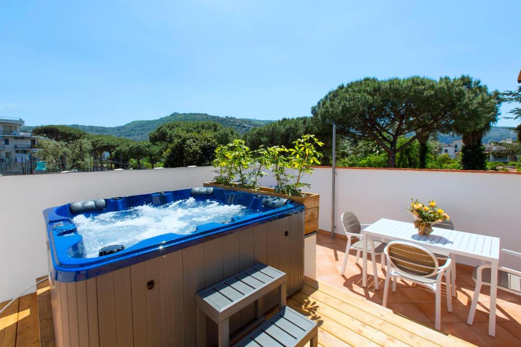 a hot tub on a deck with a table and chairs at YourHome - Jolly Pini Apartment in Sant'Agnello