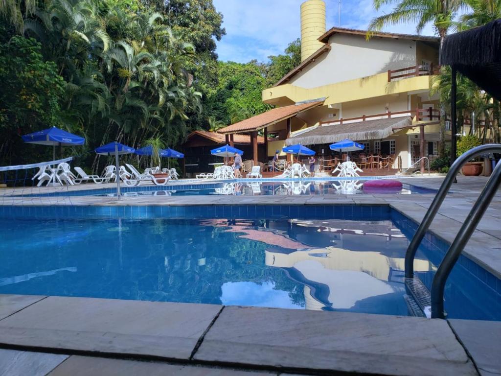 een zwembad in een resort met stoelen en parasols bij Amarilis Flat Maravilhoso - com serviço de hotelaria, sauna e piscinas climatizadas in Riviera de São Lourenço