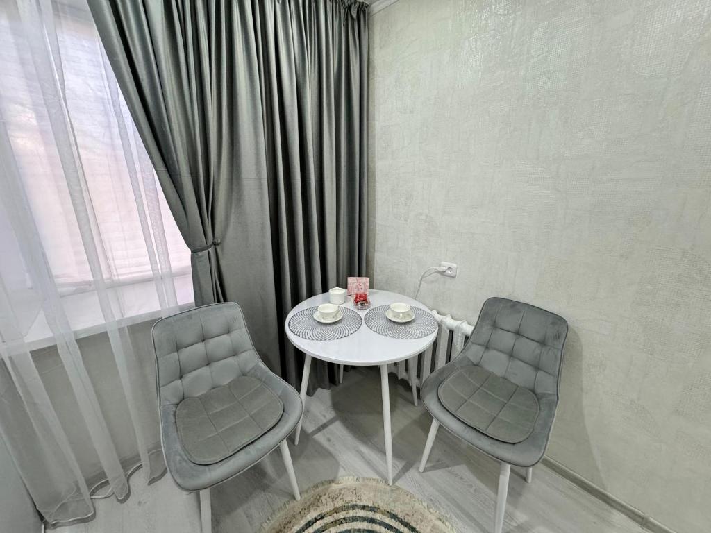 uma mesa e duas cadeiras num quarto com uma janela em 1 комнатная квартира em Oral