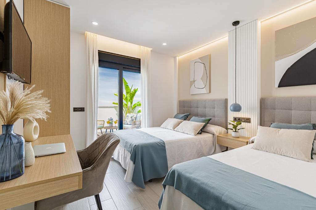 a hotel room with two beds and a desk at Stay Belonio in Málaga