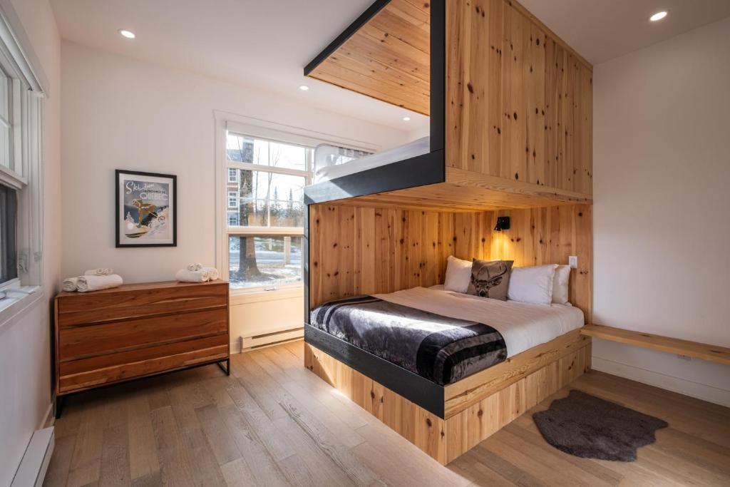 a bedroom with a bed with a wooden wall at Les Eaux 233-2-Alpine Family Escape in Mont-Tremblant