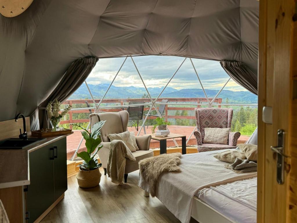 a bedroom with a bed and a large window at Tatra Glamp Tarasówka in Poronin