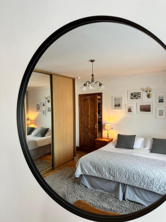 a mirror reflecting a bedroom with a bed in it at Malahide Guest Rooms in Malahide