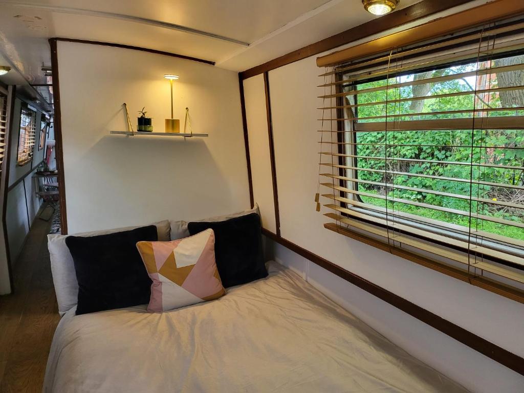 Bett in einem Zimmer mit Fenster in der Unterkunft Unique Canal Boat in London Centre for Family & Friends in London