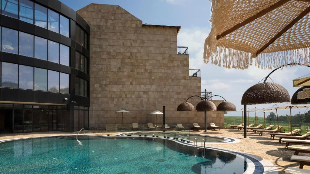 a hotel with a swimming pool in front of a building at Yarden Estate Hotel in Yesod Hamaala