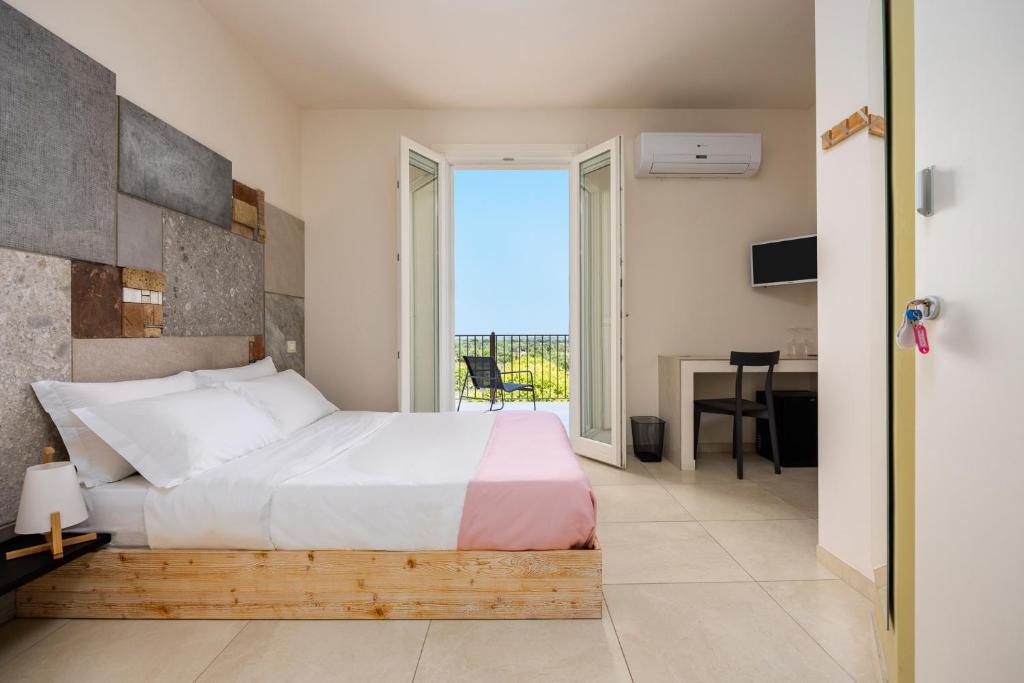 a bedroom with a bed and a desk and a window at Fiore di Vendicari B&B - Sicilian Charme, Lemon Grove and Sea in Noto