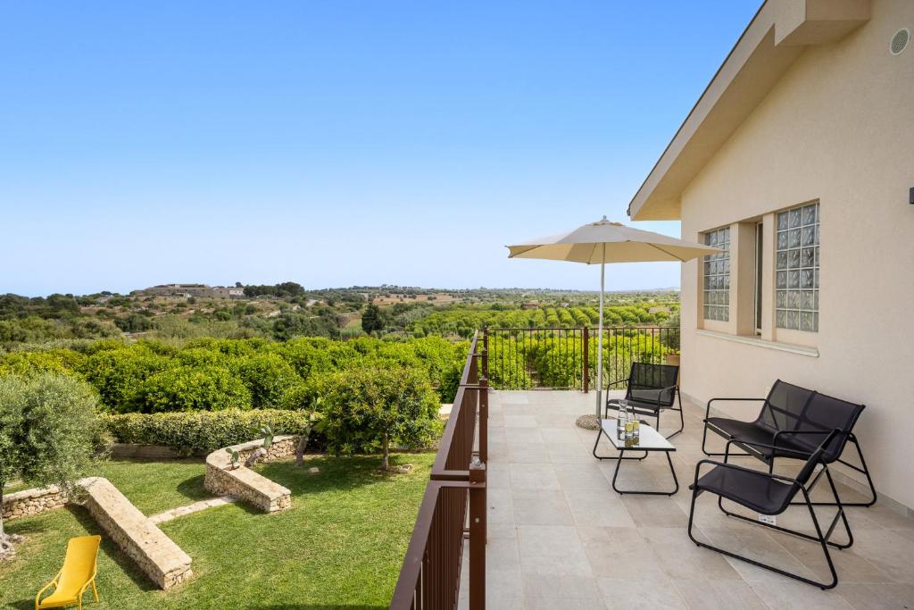a patio with chairs and an umbrella and a view at Fiore di Vendicari B&B - Sicilian Charme, Lemon Grove and Sea in Noto