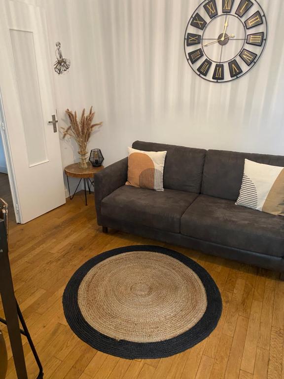 salon z kanapą i zegarem na ścianie w obiekcie Charmant 2 pièce 35m2 w mieście Montrouge