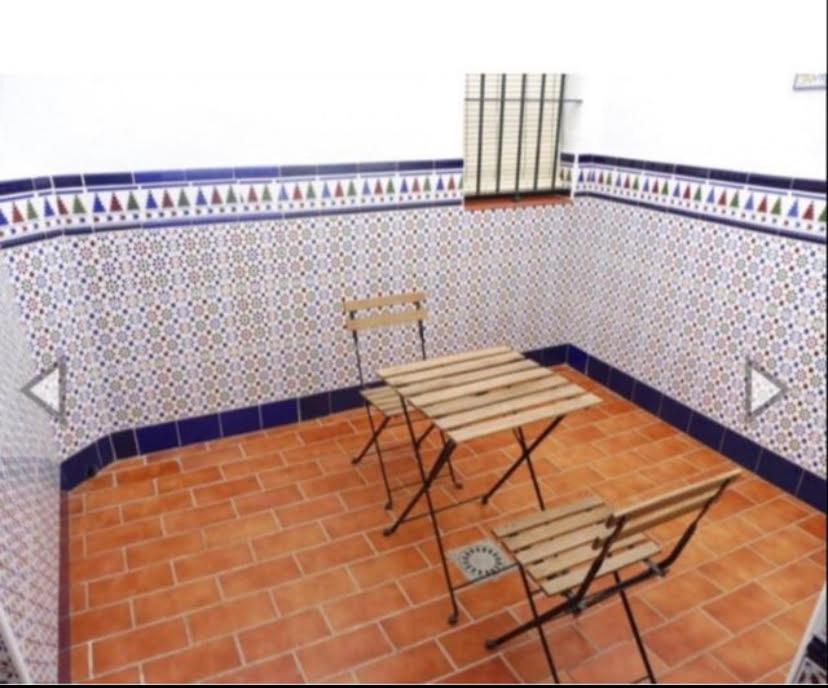 a table and chairs in a room with a wall at Duplex en centro de Chipiona in Chipiona