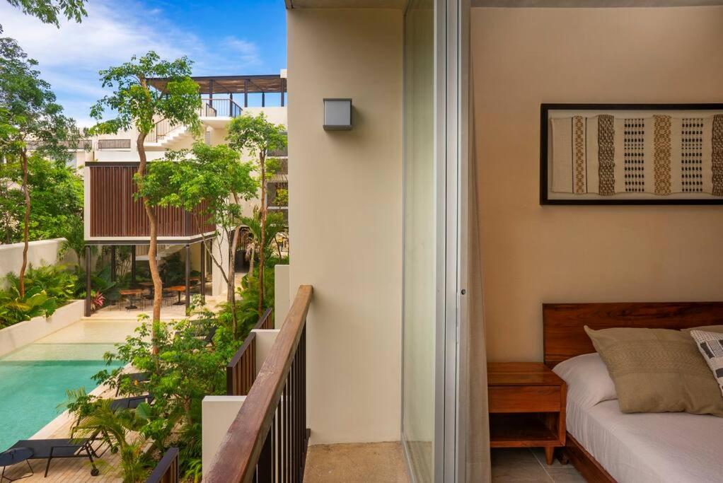 Un dormitorio con una cama y un balcón con piscina. en Modern Studio w Balcony & Pool La Veleta, - Tulum - A207, en Tulum