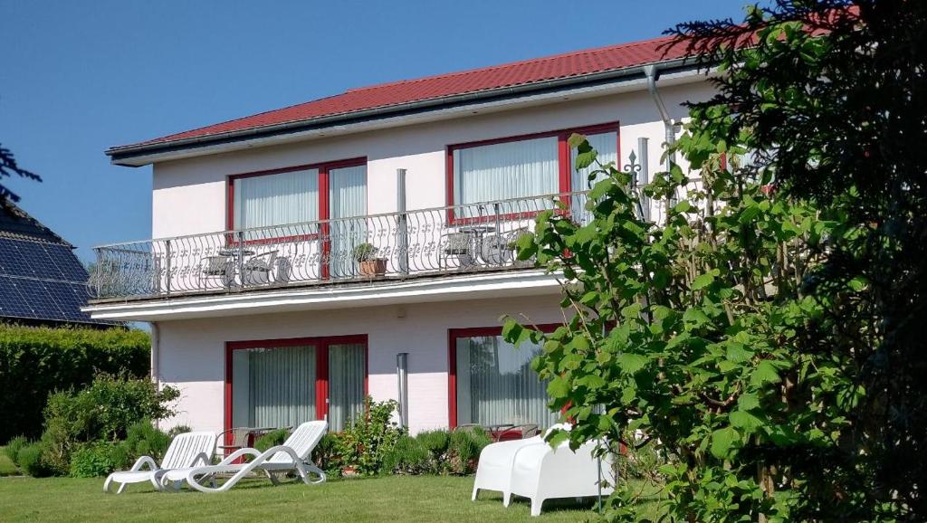 une maison avec des chaises blanches et un balcon dans l'établissement Ostseehotel Kappeln by team SchleiFee, à Kappeln