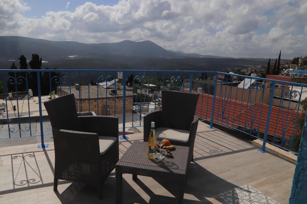 a balcony with two chairs and a table with a view at The Essence in Safed