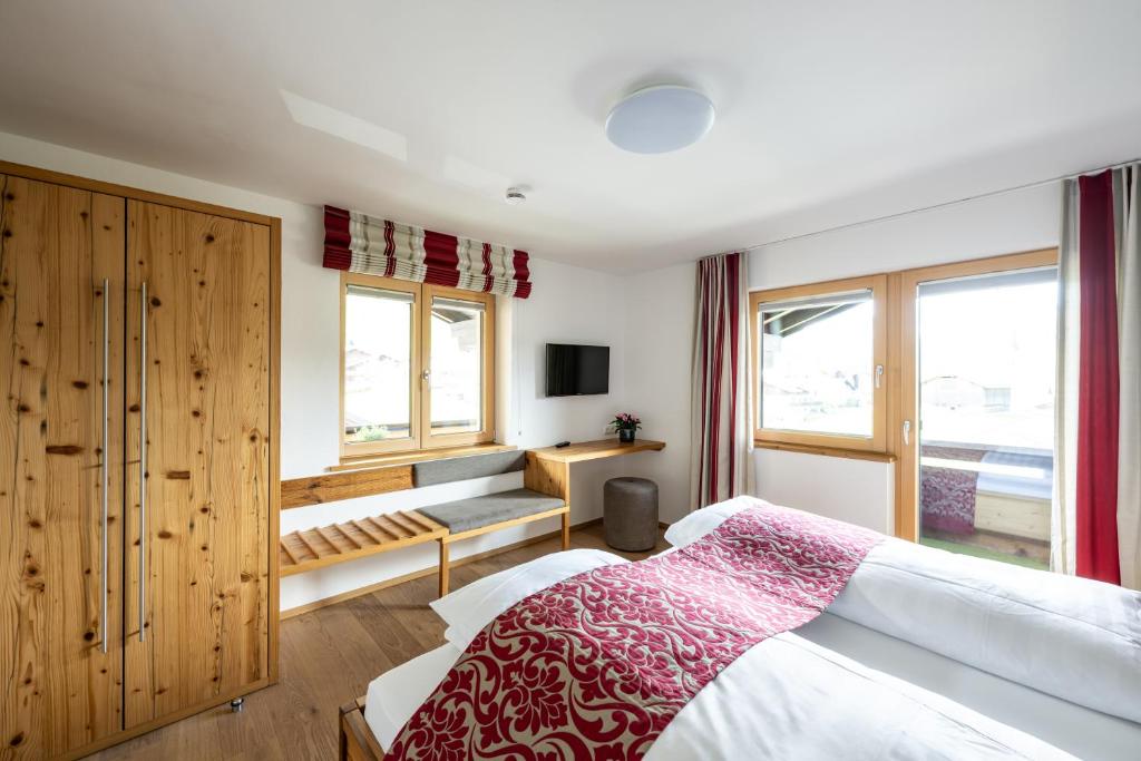 a bedroom with a bed and a desk and windows at Haus Tannberg in Riezlern