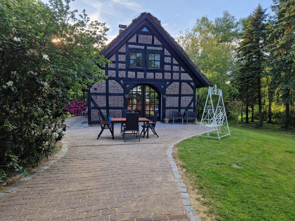 un edificio negro con una mesa y sillas en un patio en Ferienhaus Oak-Tree-Cottage, en Beverstedt