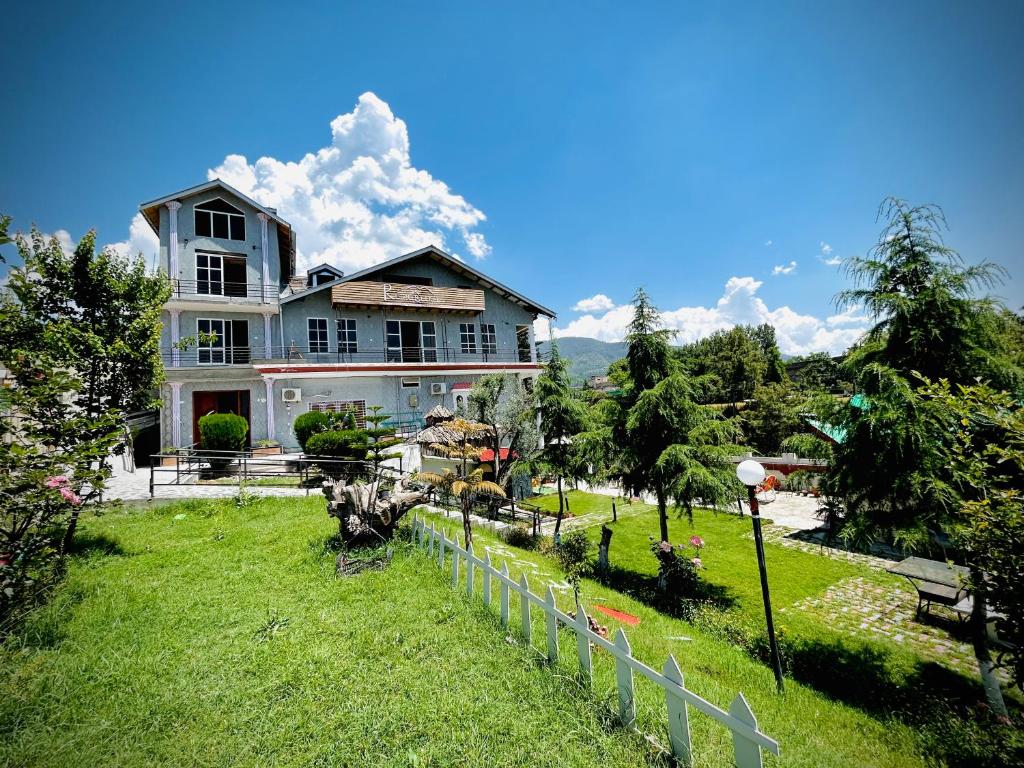 uma grande casa branca com um jardim em frente em Summit Resorts (Republika Central) em Abbottabad