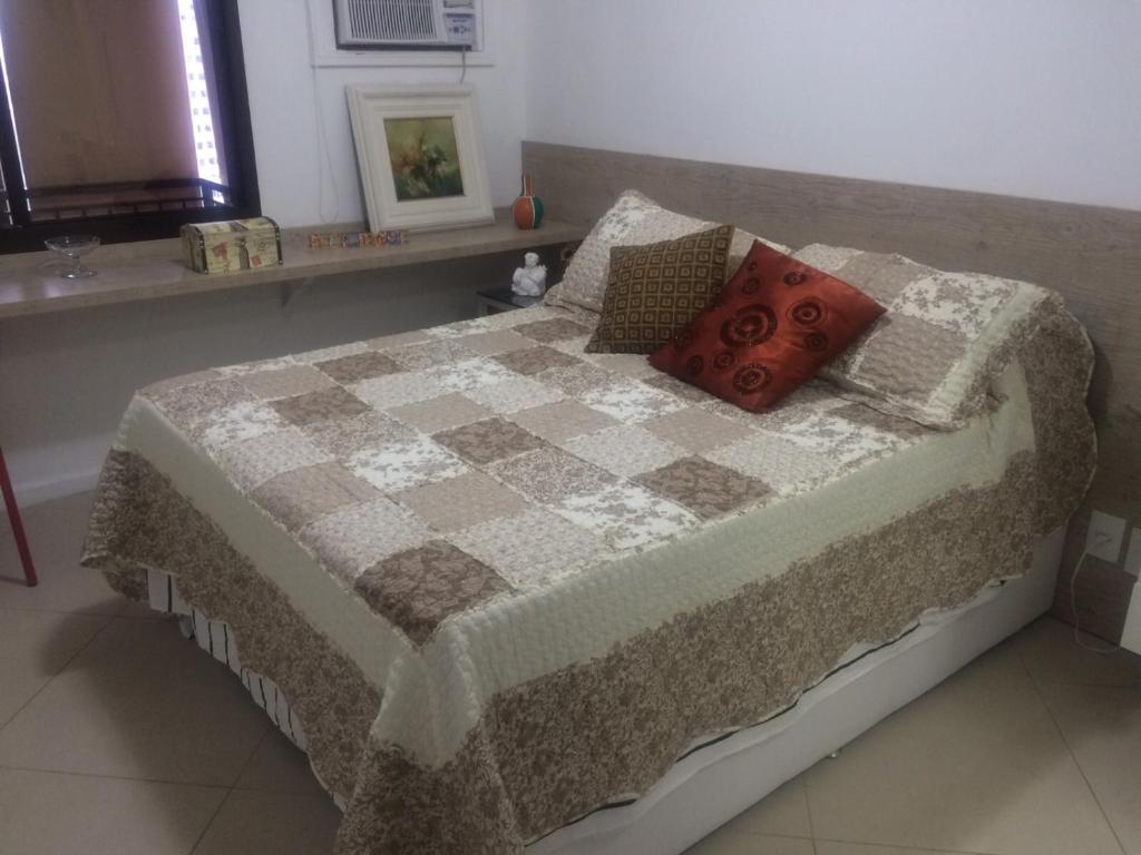 a bed with a quilt and pillows in a bedroom at Apartamento Aconchegante para sua Viagem in Rio de Janeiro