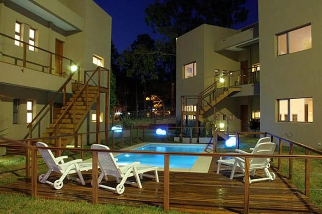 a patio with chairs and a swimming pool in front of a building at Complejo Totoras in Pinamar