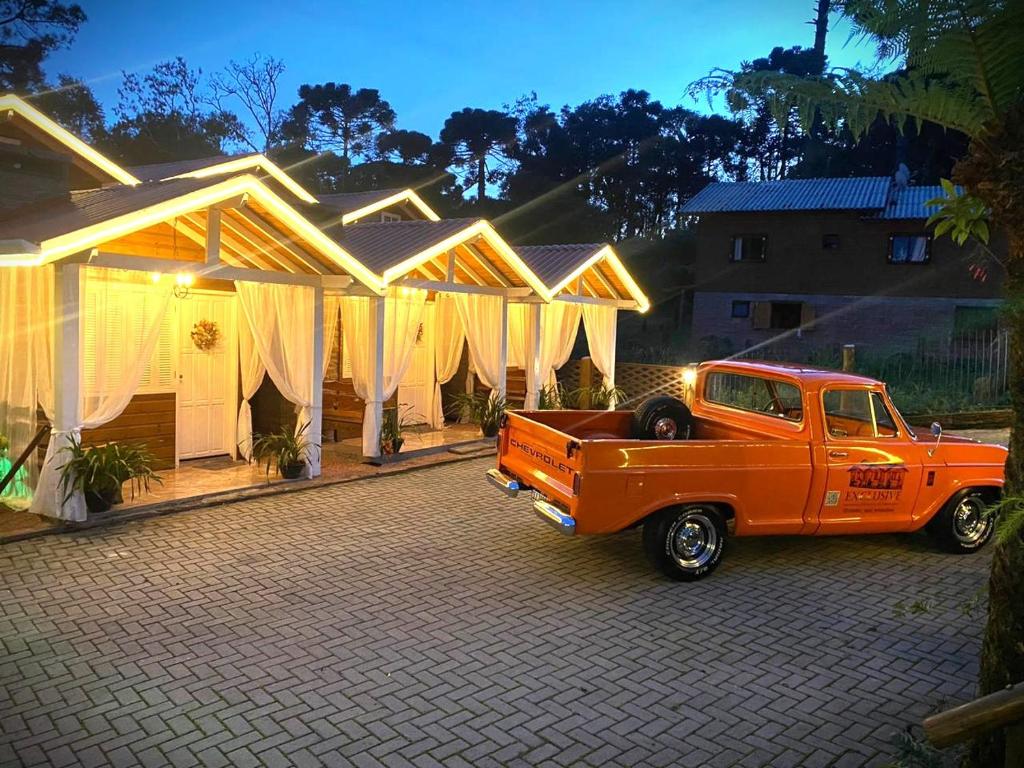 pomarańczowa ciężarówka zaparkowana przed domem w obiekcie Chales e Spa Exclusive - Localizado Proximo do Centro w mieście Canela