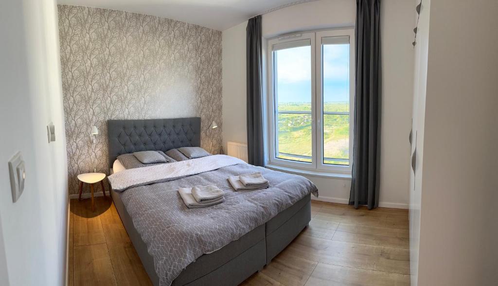 a bedroom with a bed and a large window at Prestige Aquapark Apartments - Aquatower in Reda