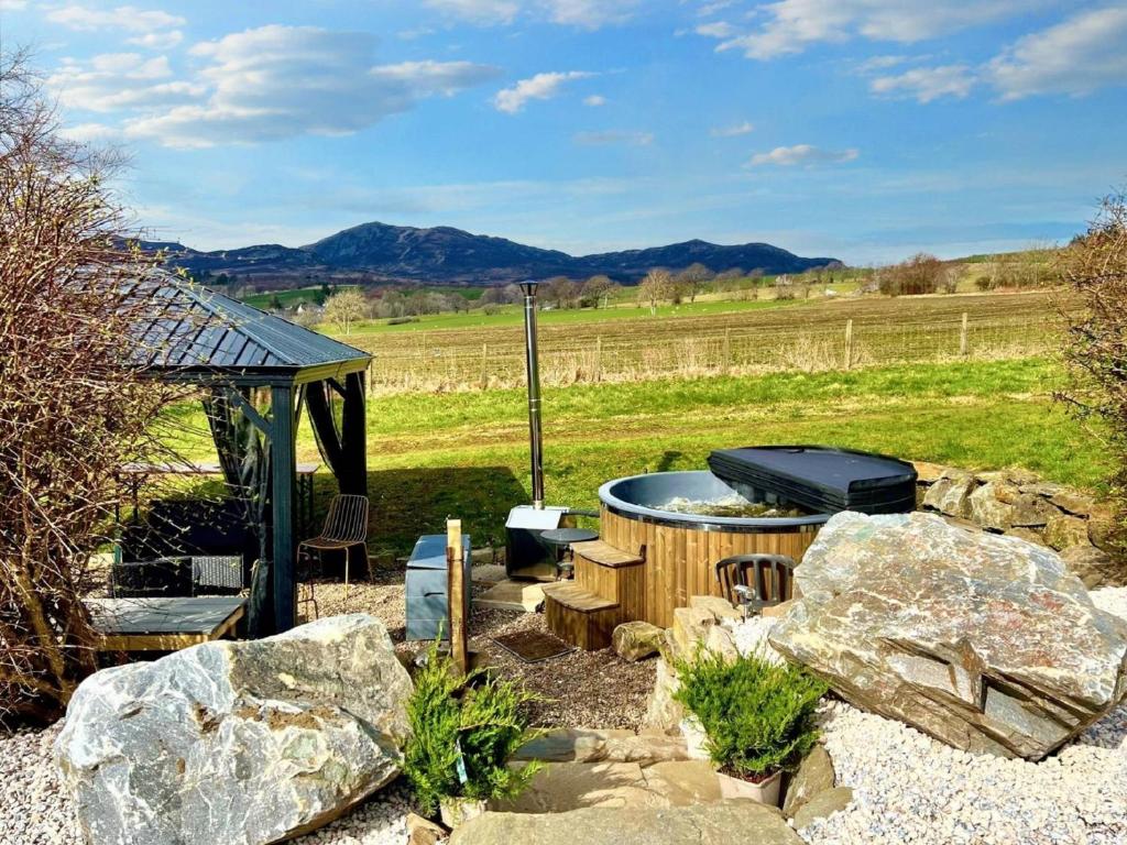 um quintal com uma banheira de hidromassagem e um grelhador e rochas em 3 Bed in Pitlochry 59677 em Pitlochry
