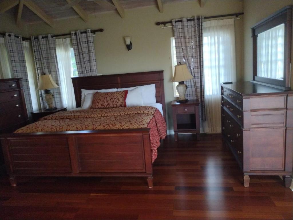 a bedroom with a bed and a dresser and windows at 4BR 3BA, Luxury Villa with Separate Pool House Access in Olveston