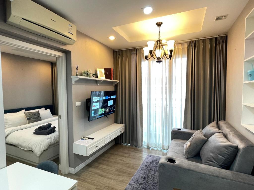 Cette chambre comprend un lit, un canapé et une télévision. dans l'établissement C sky Seaview @The Blu X, à Bang Saen