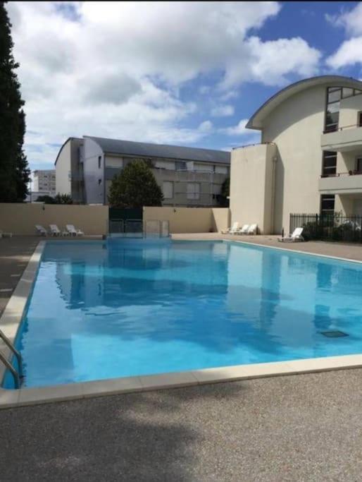 une grande piscine bleue devant un immeuble dans l'établissement Studio + piscine+ parking privé. Quartier Minimes, à La Rochelle