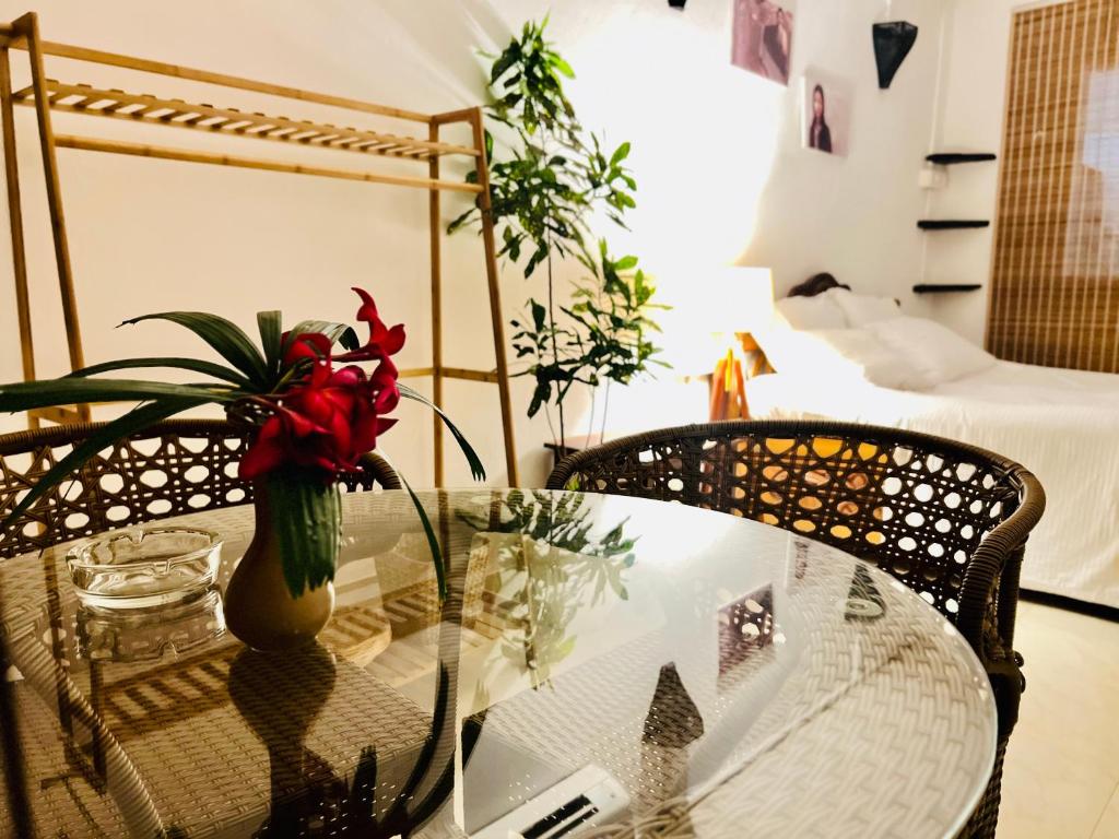 uma mesa de vidro com um vaso com flores vermelhas em Double V Arambol em Arambol
