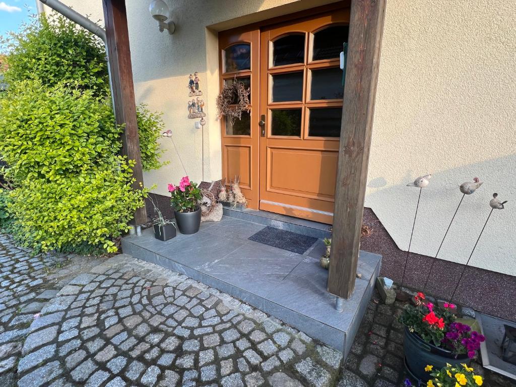 an orange door of a house with potted plants at Ferienwohnung Am Kiessee Birkwitz in Pirna