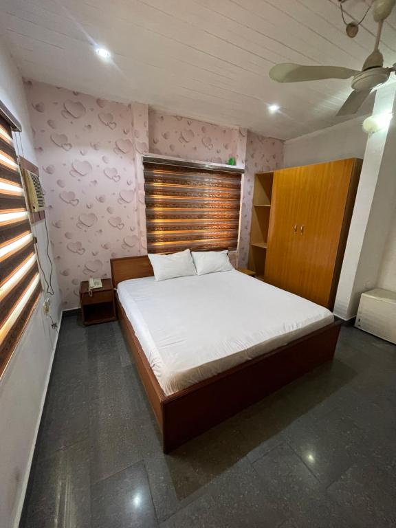 Schlafzimmer mit einem großen Bett mit einem Kopfteil aus Holz in der Unterkunft Calawazobia Hotel in Uyo