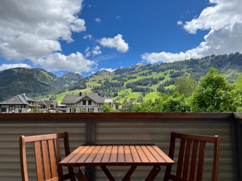 una mesa de madera y 2 sillas en un balcón con montañas en Gorgeous Apartment In The Heart Of Zweisimmen en Zweisimmen