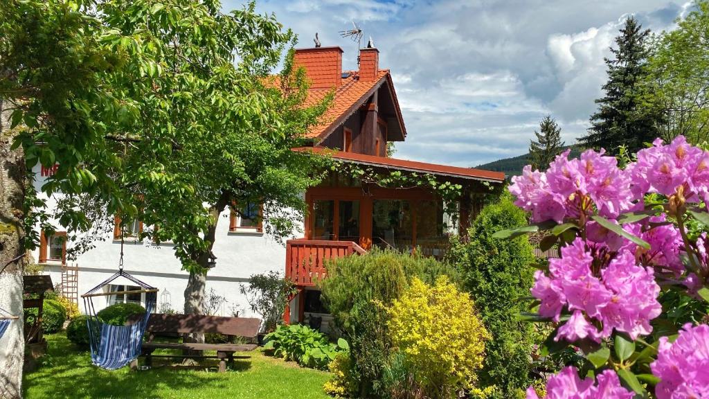 ein Haus mit einem Garten mit rosa Blumen in der Unterkunft Pensjonat Merkury in Świeradów-Zdrój