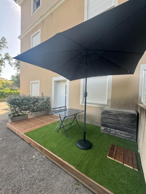 une table avec un parasol sur un carré d'herbe dans l'établissement T2 bord de mer, à Albitreccia