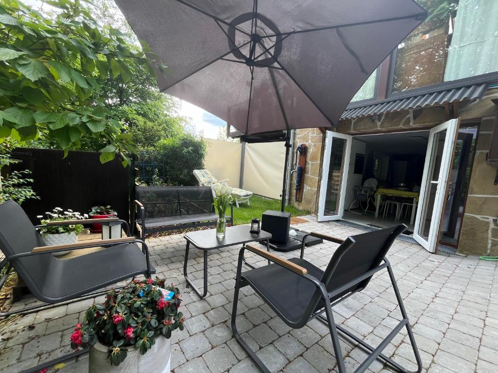 um pátio com 2 cadeiras e uma mesa com um guarda-sol em Studio renové rdc terrasse wépion (Namur) em Namur