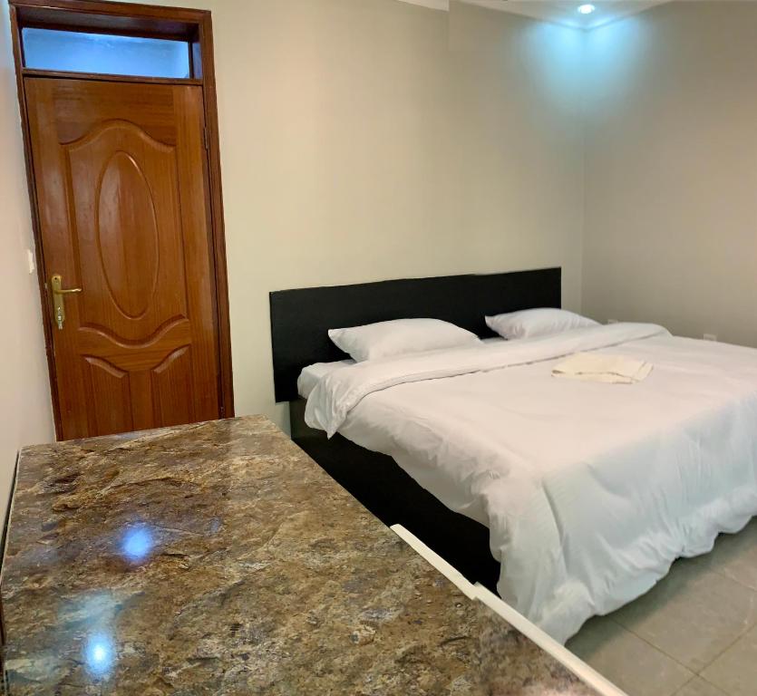 1 Schlafzimmer mit 2 Betten und einer Holztür in der Unterkunft KWETU HAVEN HOMES in Kigali