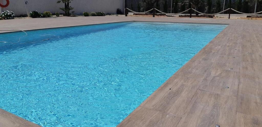 洪達海灘的住宿－Vivienda vacacional Ladera Kalblanke junto Cabo de Palos 5 personas，铺有木地板的大型蓝色游泳池