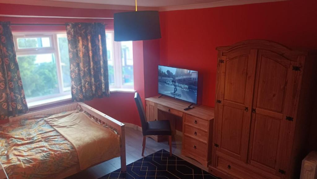 um quarto com uma cama e uma secretária com uma televisão em L'Auberge em Londres