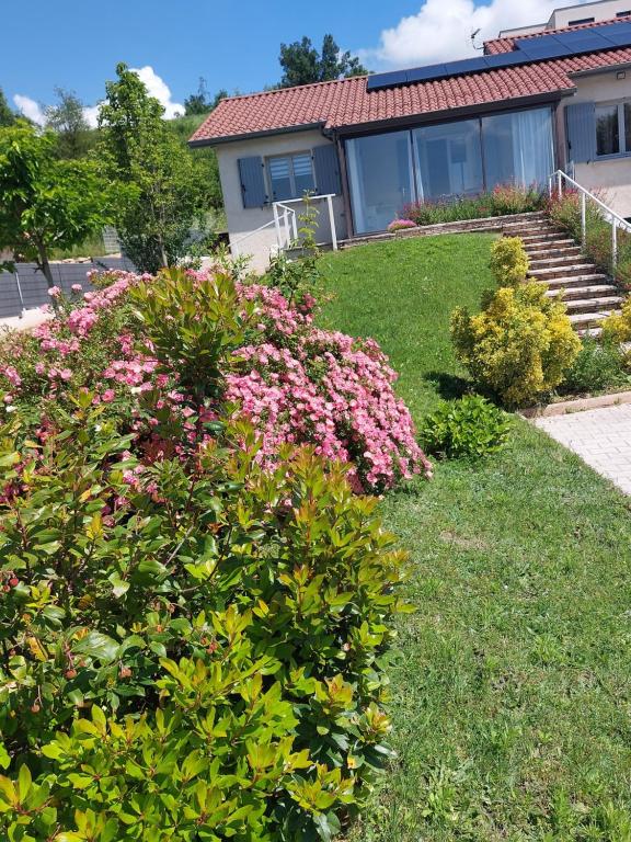 een tuin met roze bloemen voor een huis bij Gite des Reguinelles in Saint-Lattier